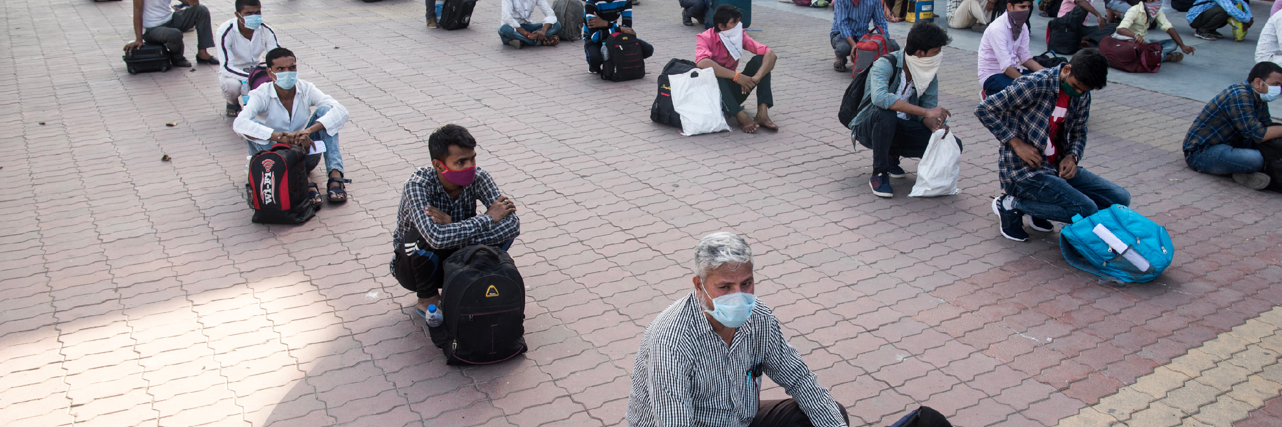 Mumbai, India. Los trabajadores migrantes se sientan en la cola en una terminal de tren para abordar un tren para su viaje de regreso a casa durante un cierre nacional.